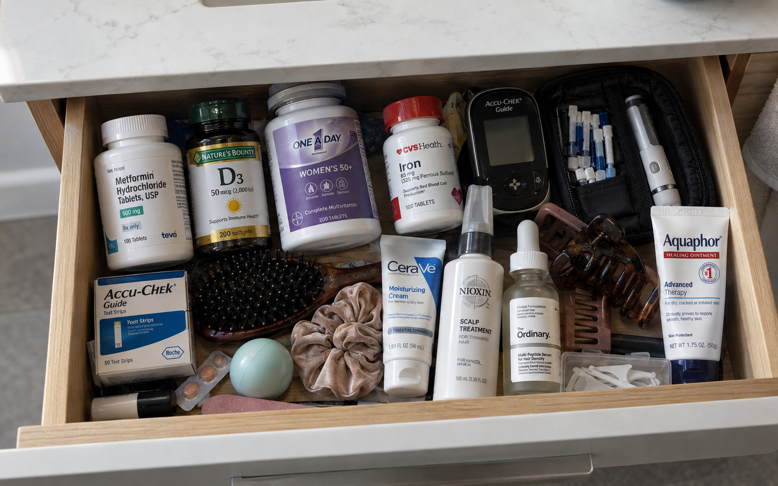 An open bathroom drawer filled with diabetes medications, supplements, test strips and hair products